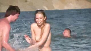 A mature woman sunbathes naked on the beach, showing her body parts