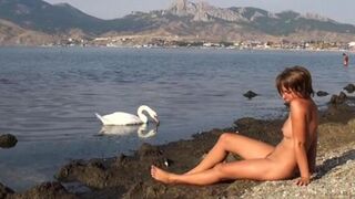 A girl walked naked on the riverbank, feeling the wind in her hair