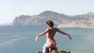 A young girl poses naked on the sandy coast of the sea