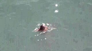 A pair of naturists swim naked in the sea, enjoying freedom