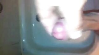 The kid caresses his cock with his hand in the shower stream