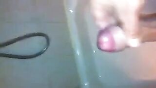 The kid caresses his cock with his hand in the shower stream