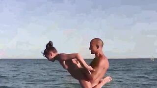 A naked acrobat is exercising on the nude beach